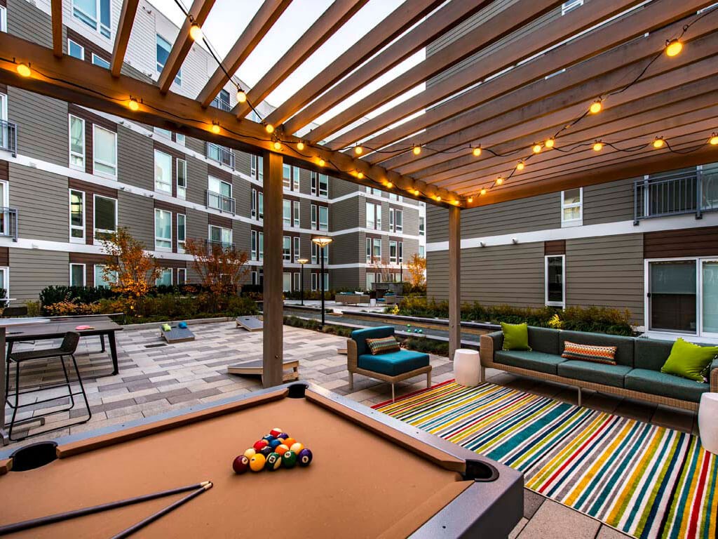 Outdoor seating areas with pool table and pergola above