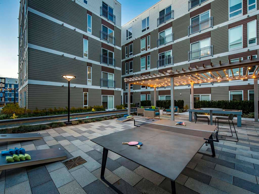 Dusk view of outdoor lounge with ping pong and cornhole outdoor games