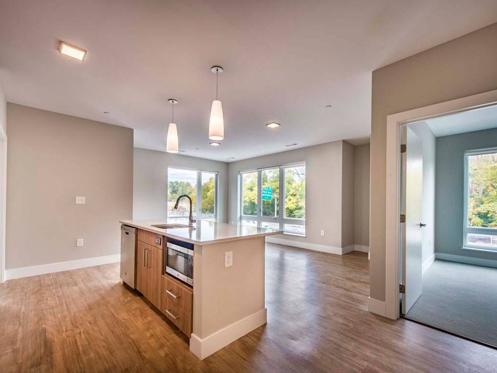 View of vacant apartment showing island and multiple windows in living space