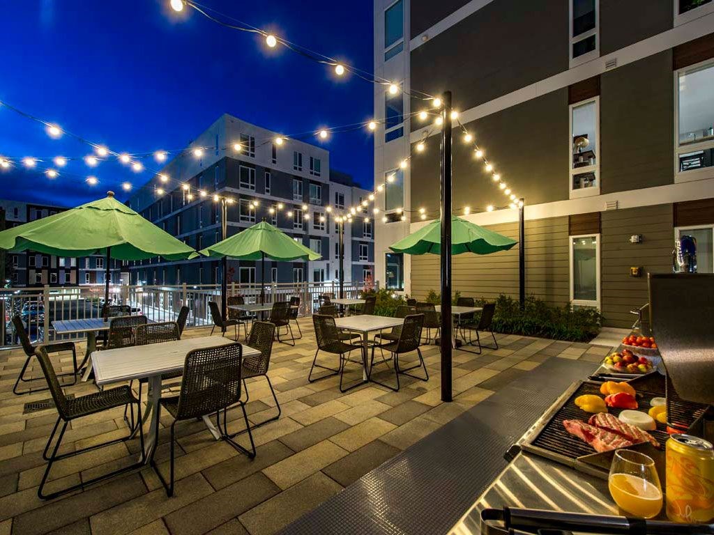 Dusk view of outdoor grill with dining tables and chairs