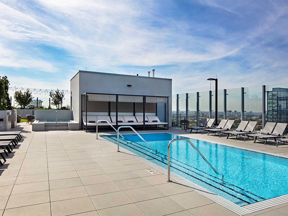 the pool on the rooftop of a building with lounge chairs