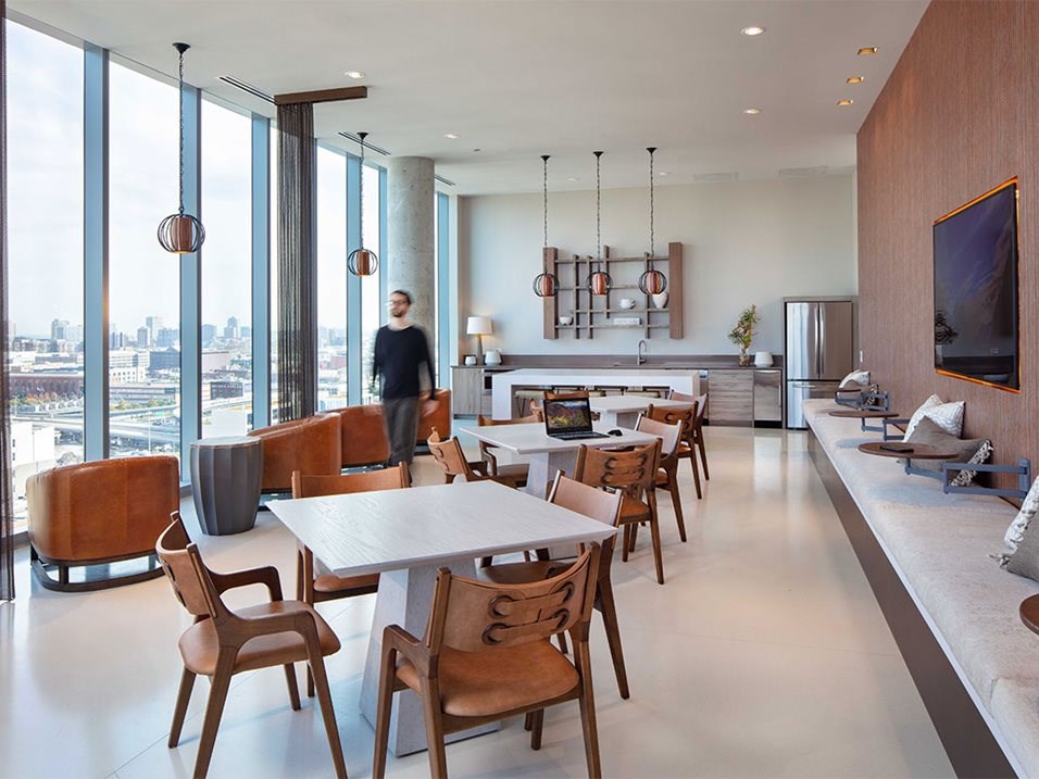 a man walking through a living room with tables and chairs