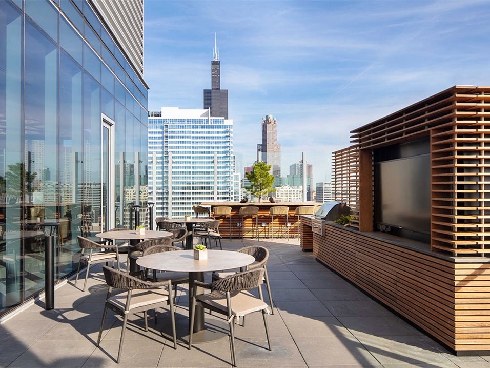 a terrace with tables and chairs and a television on the side of a building
