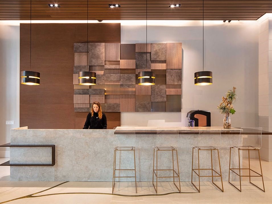a woman stands at a reception desk in a hotel lobby