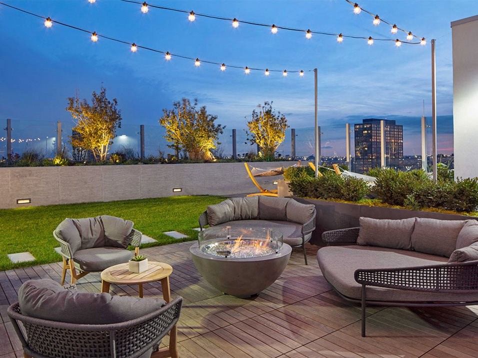 a rooftop patio with couches and chairs and a fire pit