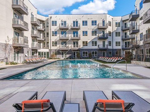 Sparkling resort style swimming pool with cushioned lounge chairs