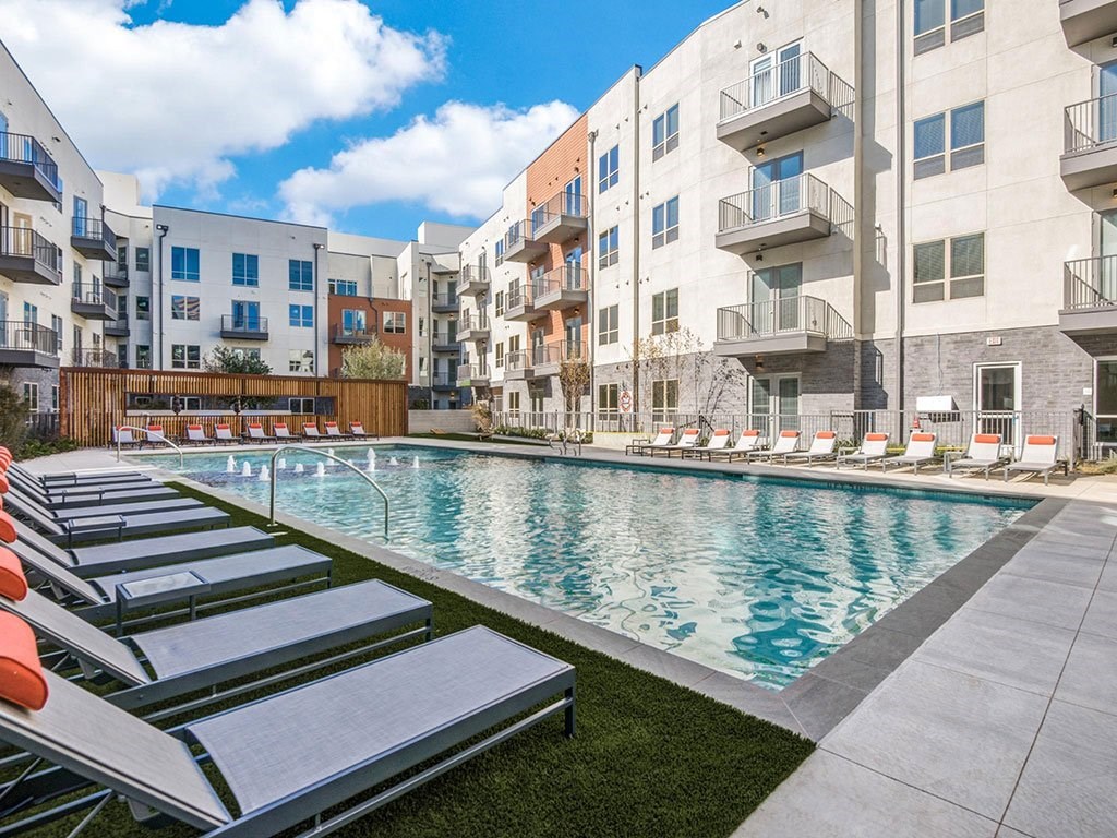 Sparkling resort style swimming pool with cushioned lounge chairs