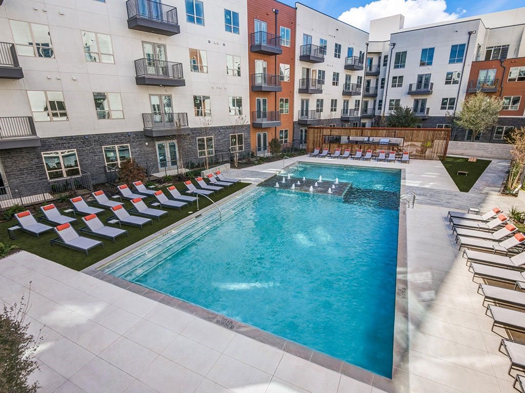 Sparkling resort style swimming pool with cushioned lounge chairs