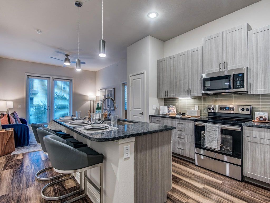 Granite counter tops, stainless appliance package, medium brown cabinets, plank wood-style flooring, island seating, abundant cabinet and pantry space