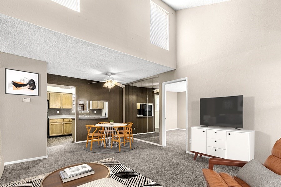 Generously sized living room seamlessly integrated with an open-concept kitchen, adorned with carpet flooring and illuminated by ample natural lighting