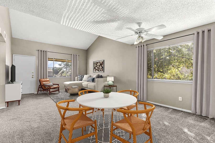 Living room with carpet flooring, equipped with a ceiling fan for added comfort, and large windows which invite ample natural light into the space.