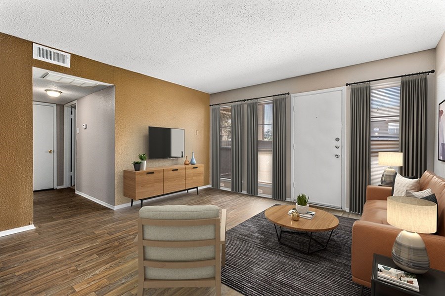 Expansive living room with hardwood floors, featuring windows and a door that opens to a balcony, allowing abundant natural light to fill the space