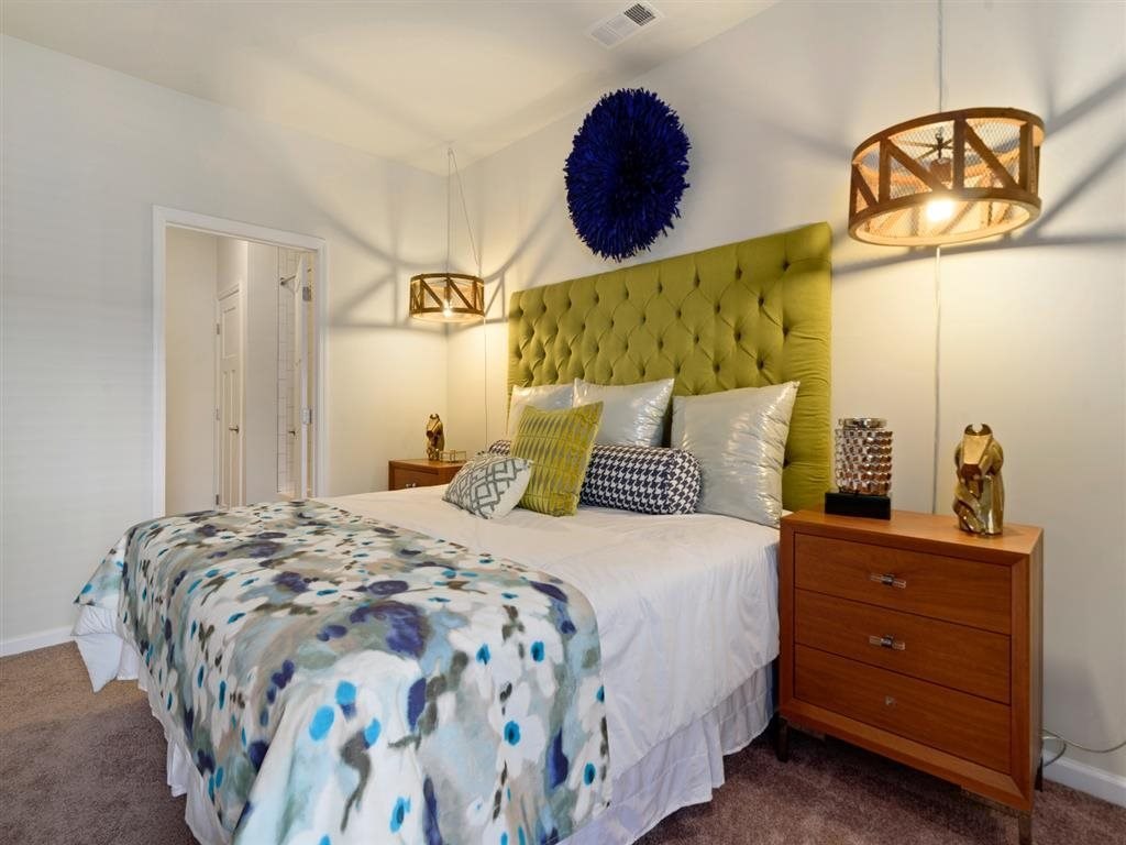 a bedroom with a bed with a green headboard and two night stands