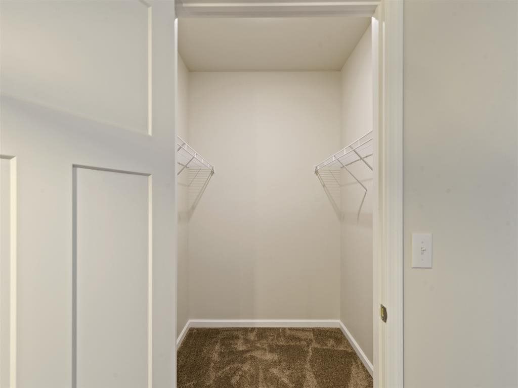 a closet in a white room with hanging racks