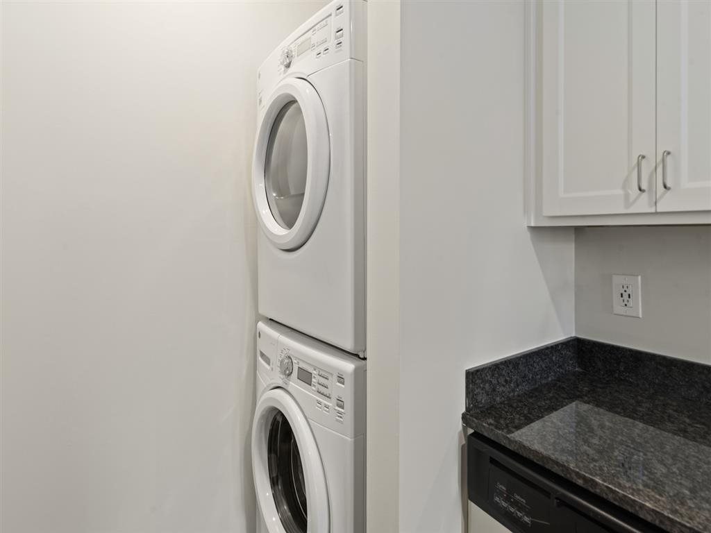 a white washer and dryer in a kitchen with white cabinets