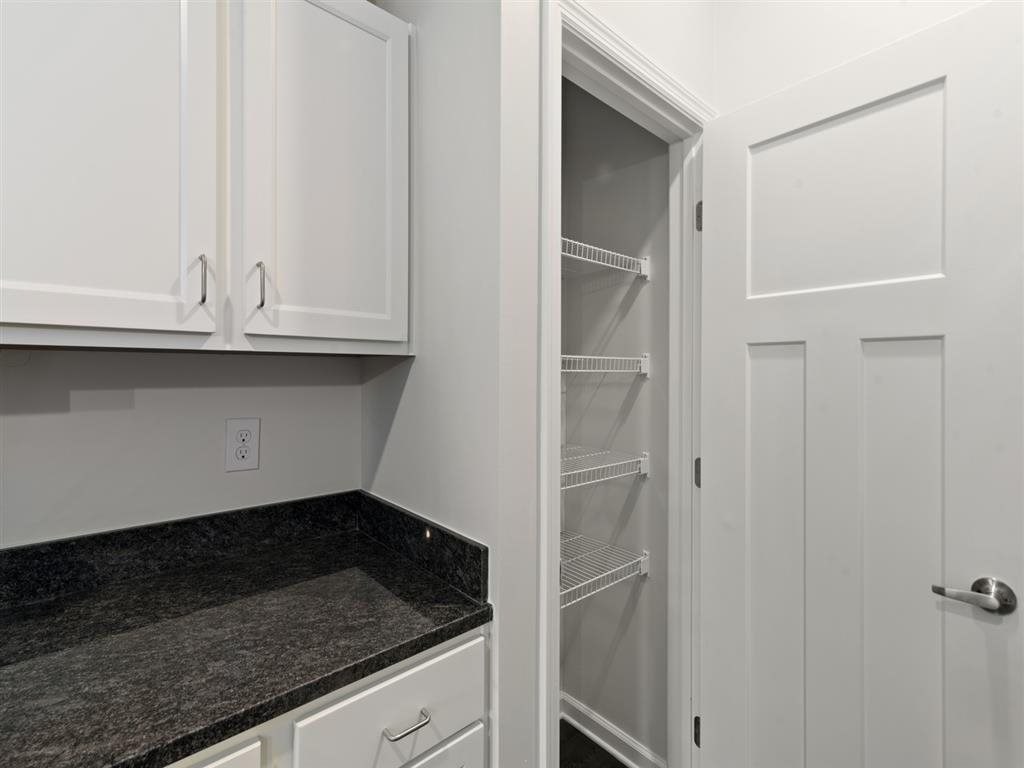 a kitchen with white cabinets and a door to an empty closet