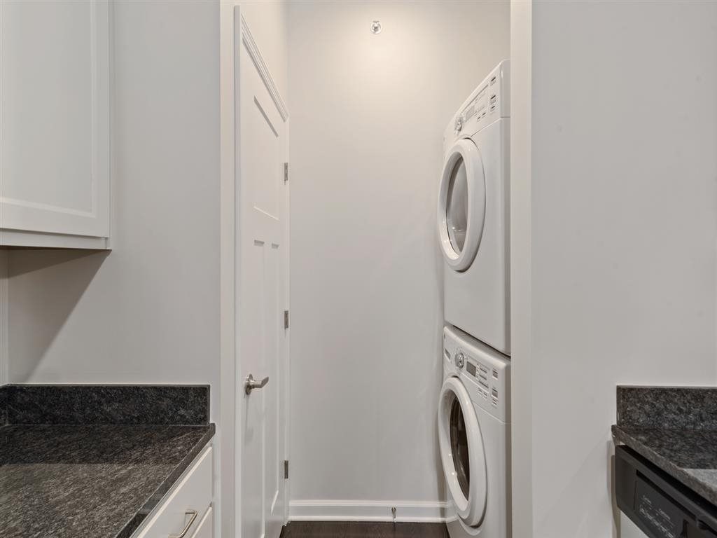 a white laundry room with a washer and dryer and white cabinets