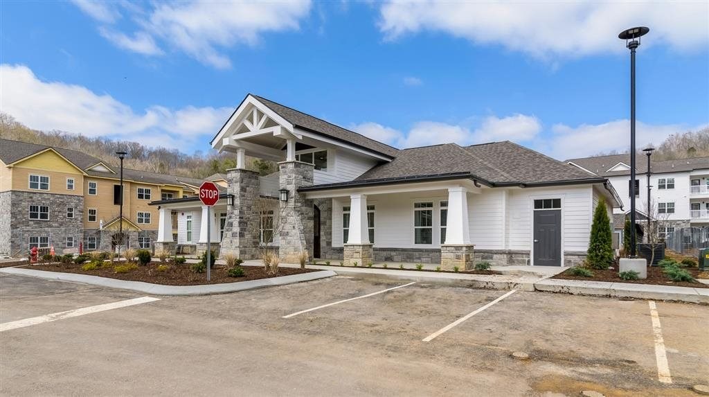 an empty parking lot in front of a house with a stop sign