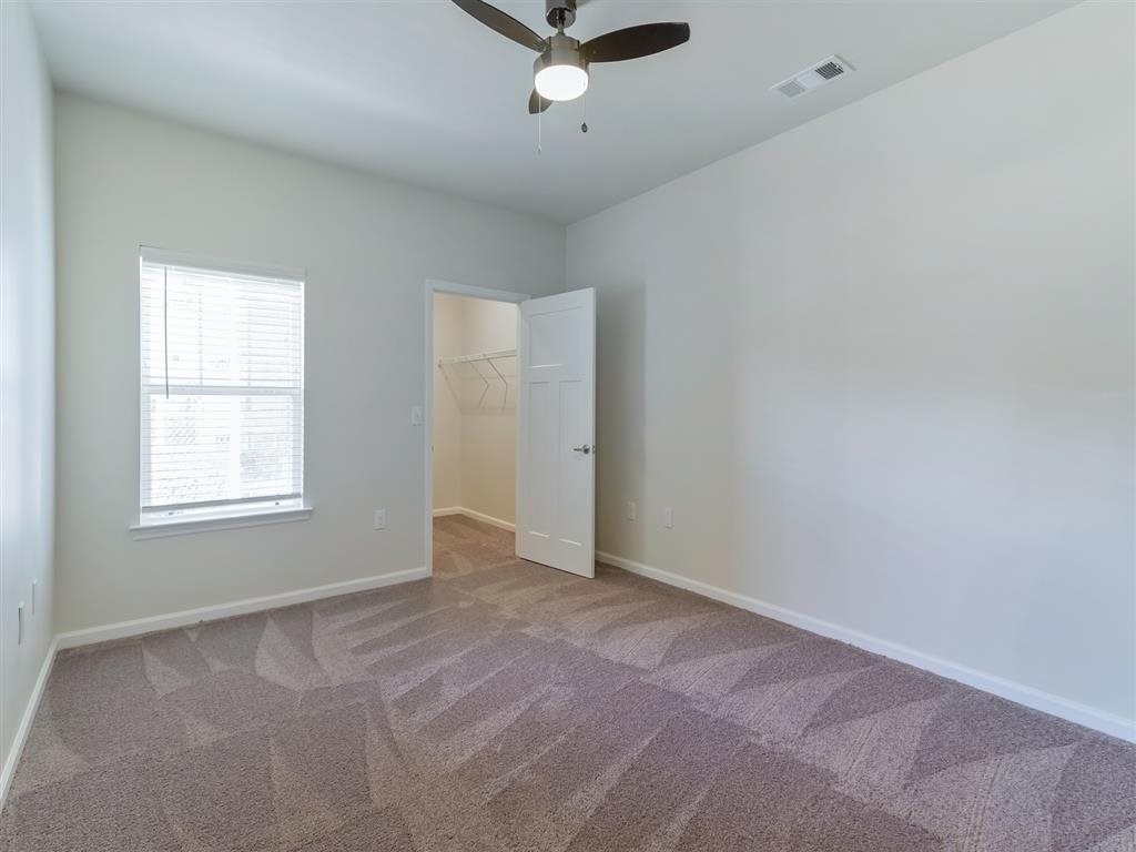 an empty living room with a ceiling fan and a closet