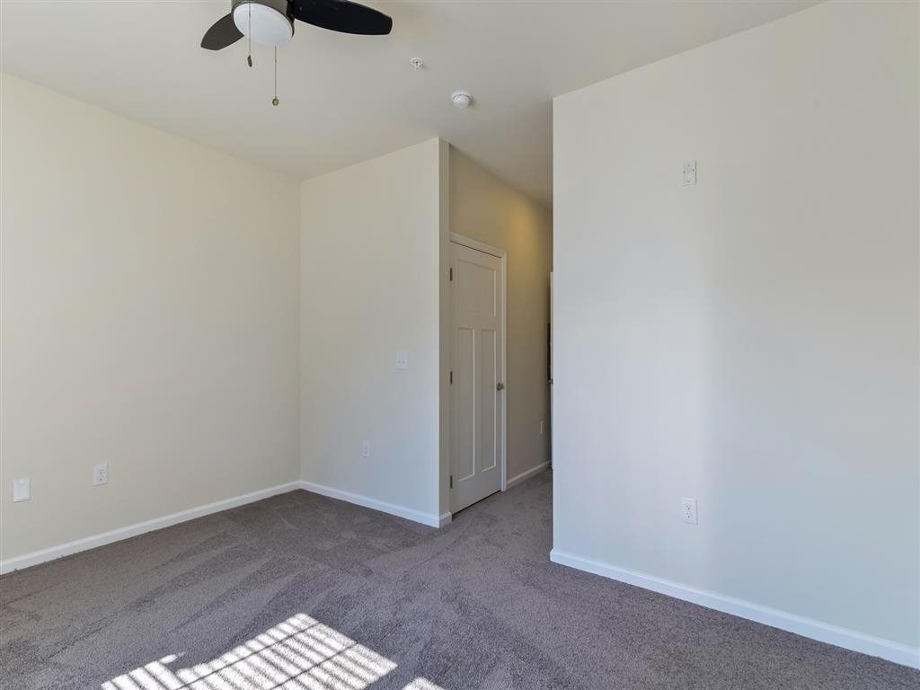 a living room with white walls and a ceiling fan