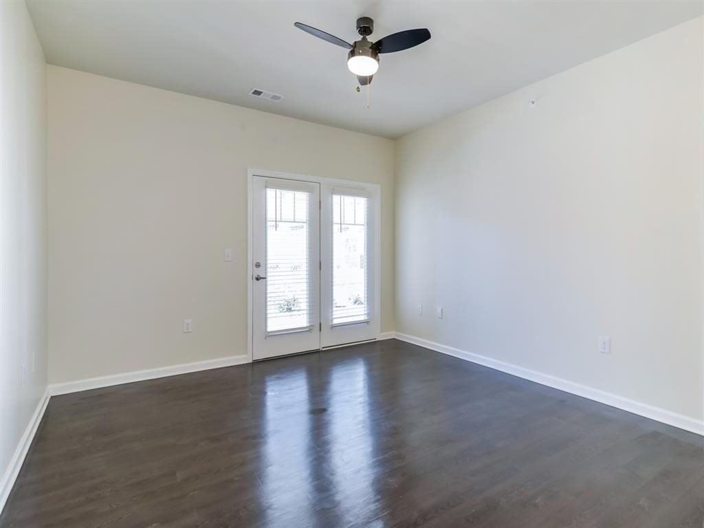 an empty living room with white walls and a ceiling fan