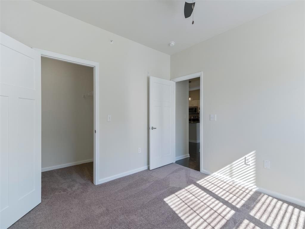 a bedroom with a carpeted floor and a door to a closet