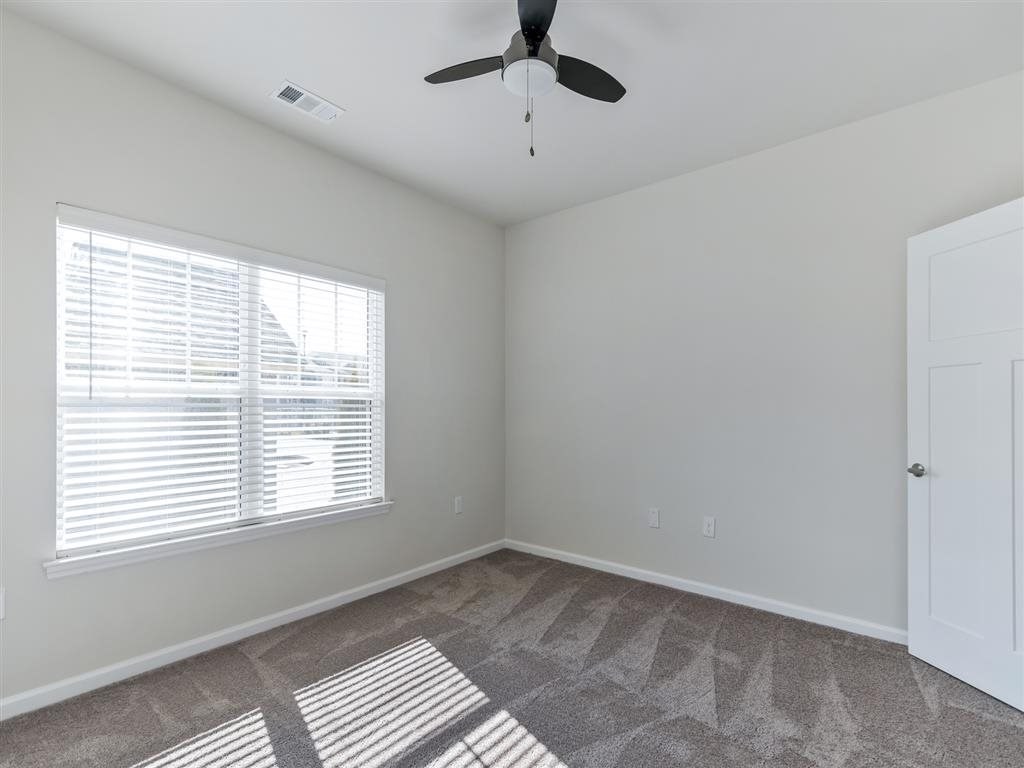 an empty bedroom with a window and a ceiling fan
