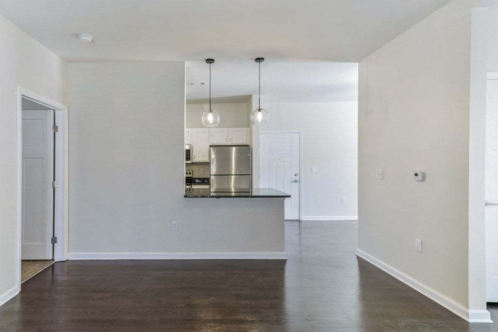an empty living room with white walls and a kitchen