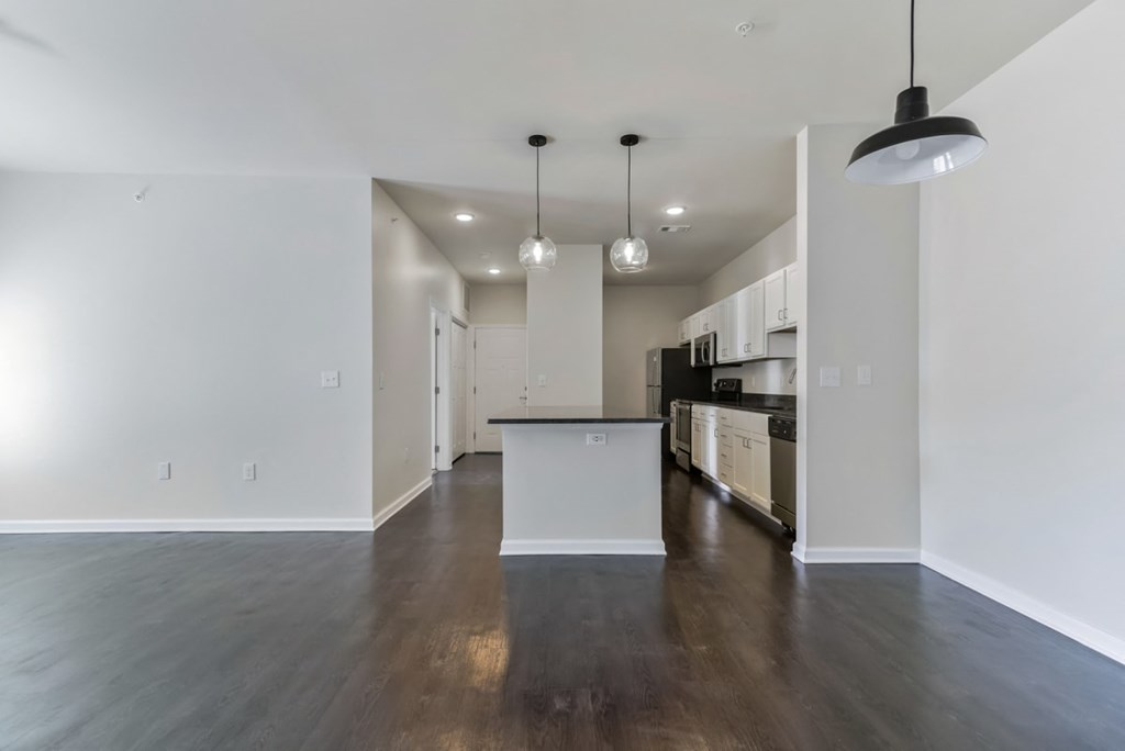 a living room and kitchen with white walls and wood floors