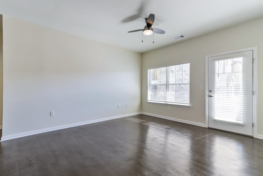 an empty living room with a ceiling fan and a window