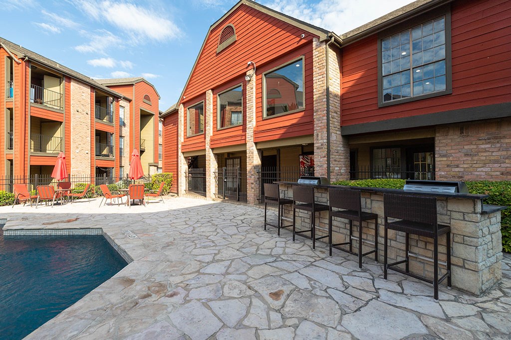 a patio with a pool and chairs in front of a building