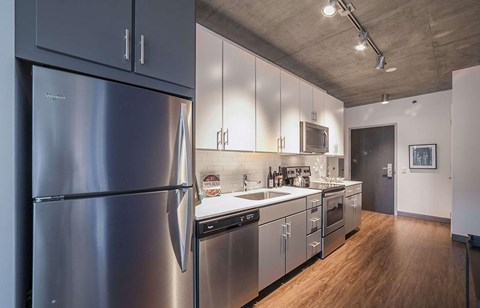 A modern kitchen with a stainless steel refrigerator and wooden floors.