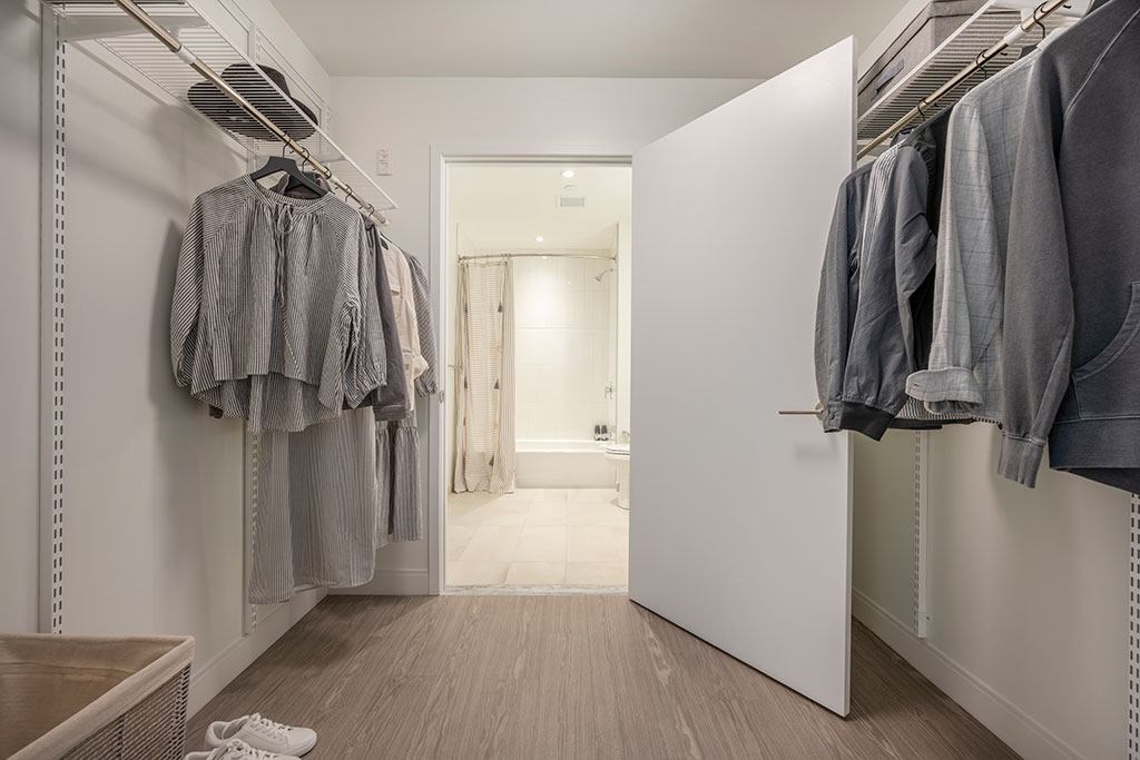 Walk-in closet with shelving connected to bathroom