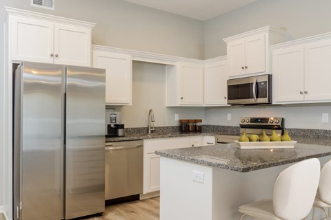 A kitchen with a stainless steel refrigerator and white cabinets.
