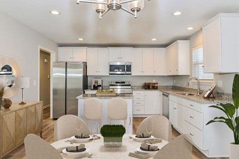 A modern kitchen with a dining table set for two.