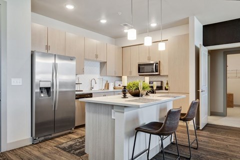 a kitchen with a large island and a stainless steel refrigerator