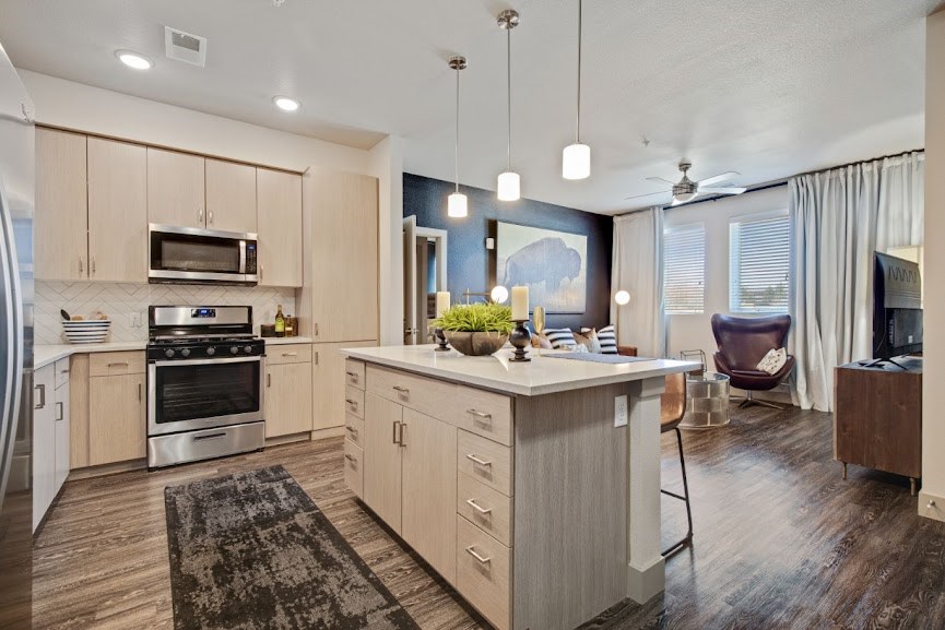 a kitchen with an island and a living room in the background