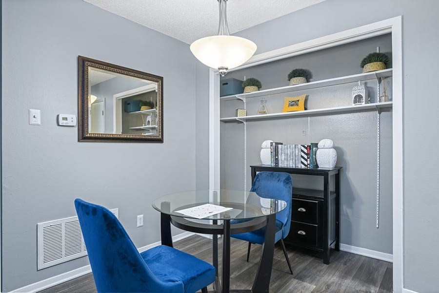 a dining room with a glass table and two blue chairs