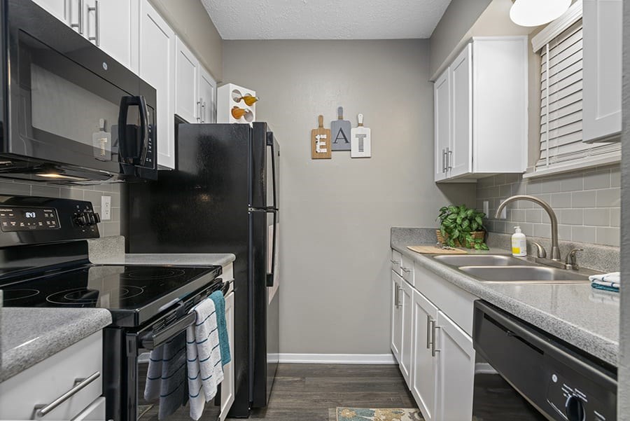 a kitchen with white cabinets and black appliances