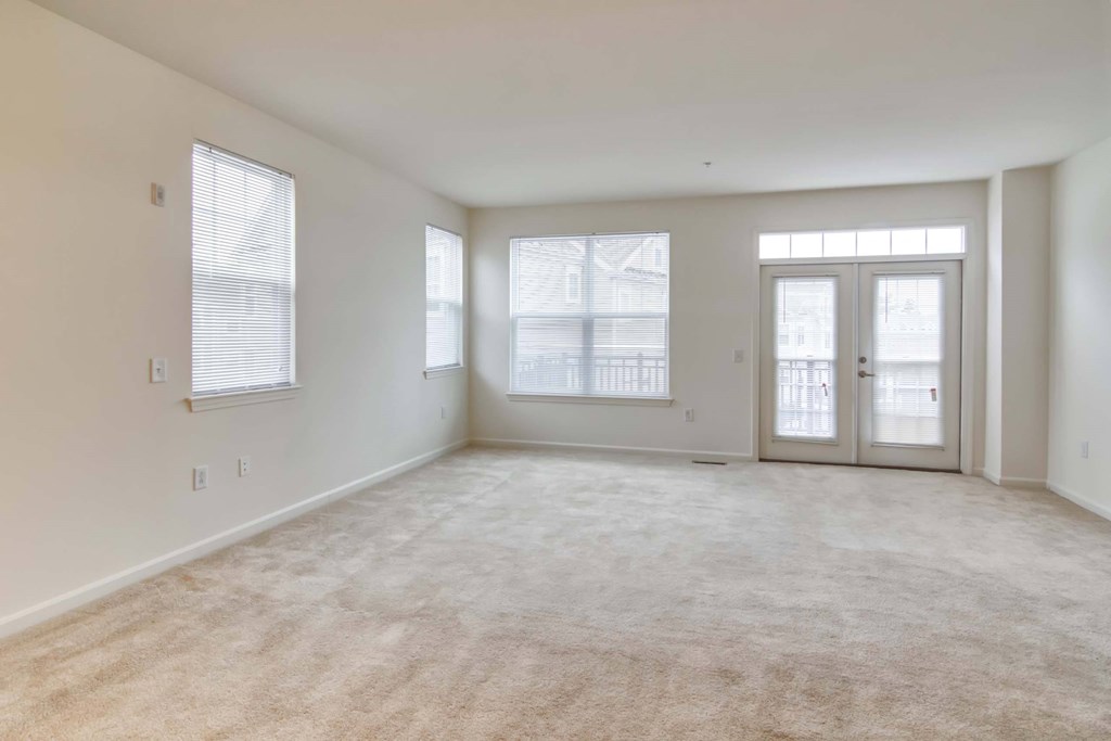 the living room of an empty home with white walls and carpet