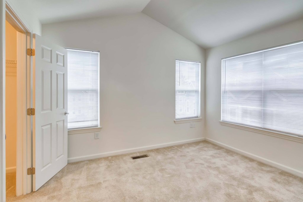 an empty room with a door and three windows