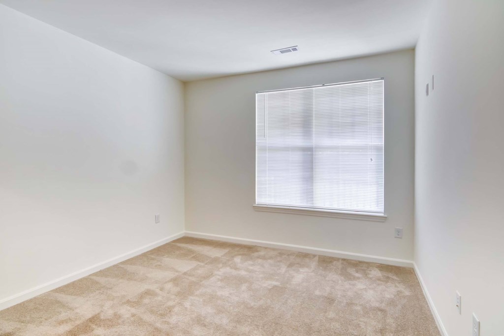 a bedroom with a window and a carpeted floor