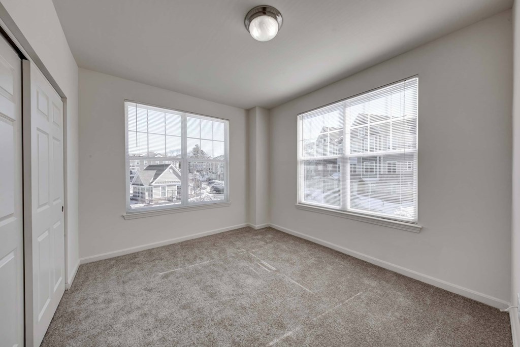 an empty living room with two windows and a door