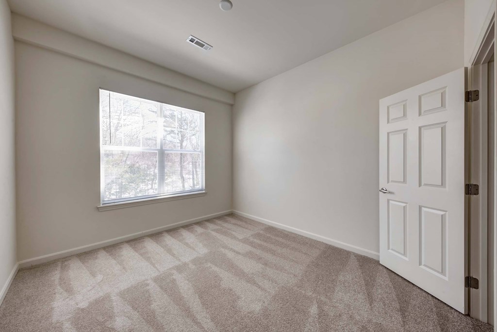 an empty bedroom with a window and a door