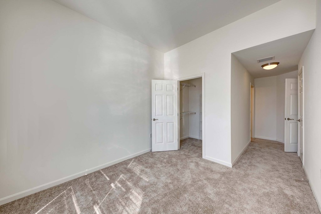 a bedroom with white walls and a door to a closet