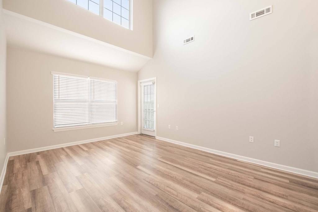 an empty living room with hardwood flooring and a window