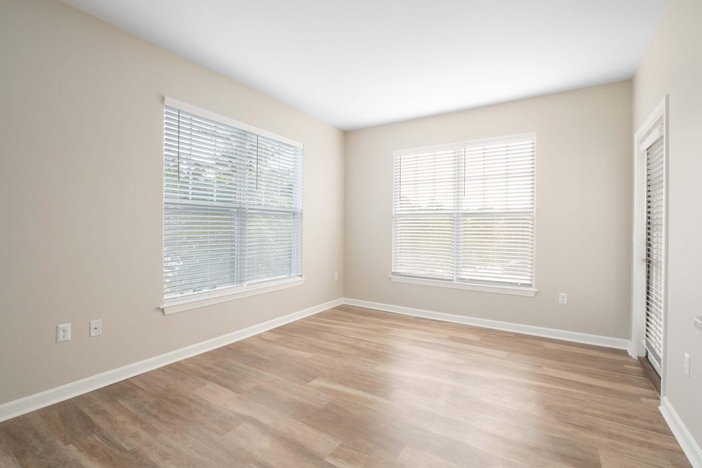an empty living room with wood flooring and windows