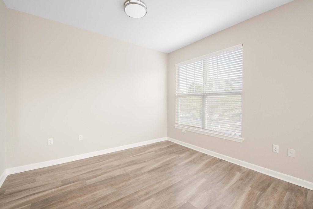 an empty living room with wood floors and a window