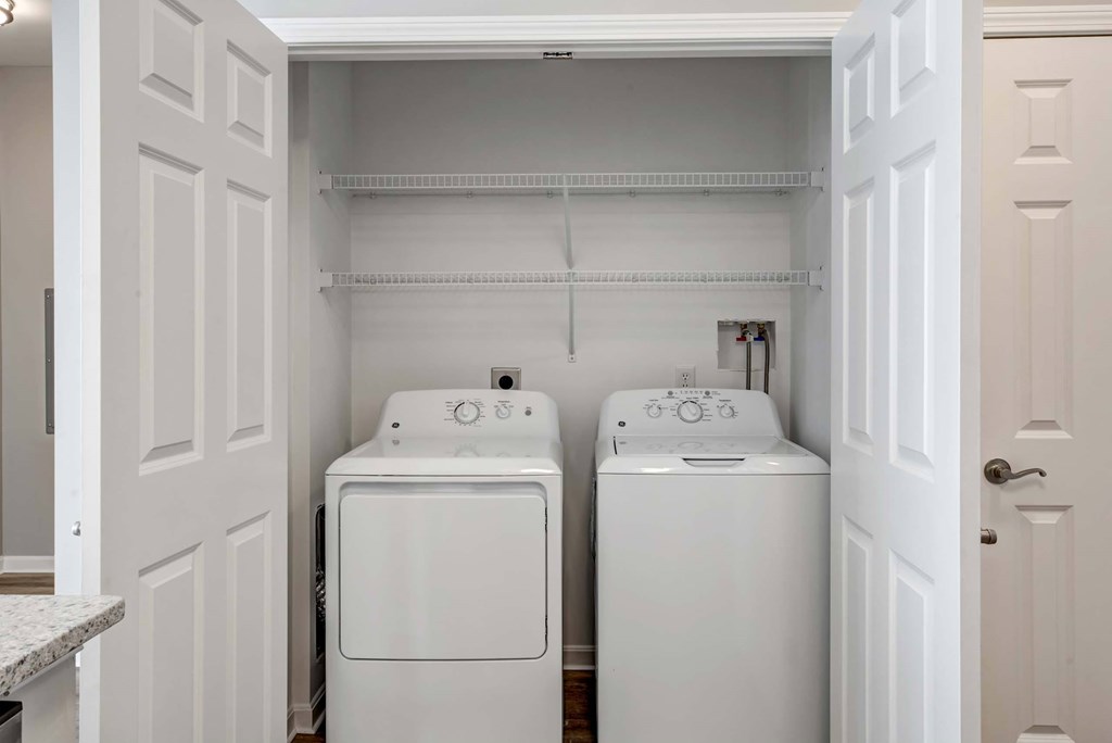 a washer and dryer in a laundry room with white cabinets