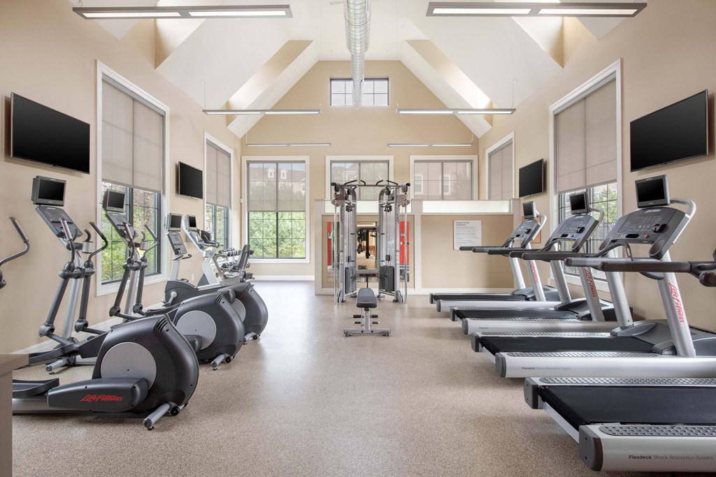 a gym with cardio machines and televisions